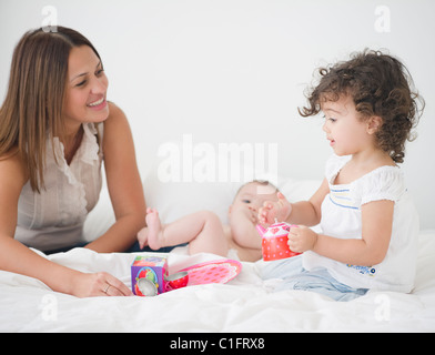 Madre avente tea party sul letto con le figlie Foto Stock