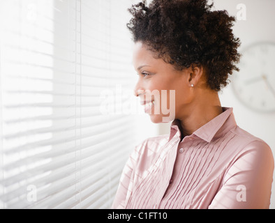 Imprenditrice nero a guardare fuori dalla finestra Foto Stock