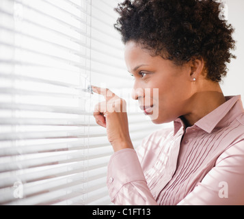 Imprenditrice nero a guardare fuori dalla finestra Foto Stock