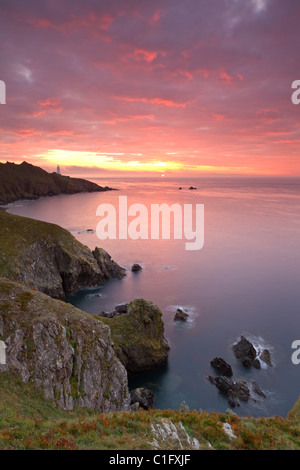 Sunrise glorioso al largo delle coste del punto di inizio con il faro sul promontorio distante, Sud prosciutti, Devon, Inghilterra. Foto Stock