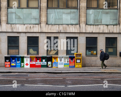 Un uomo cammina passato i numerosi quotidiani internazionali in vendita a Londra. Foto Stock