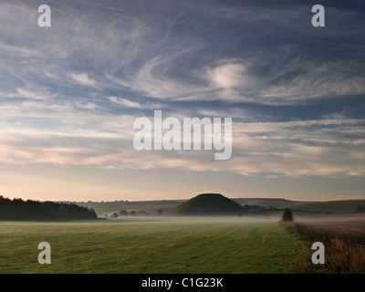 Vista su campo nebbioso di Silbury Hill sotto le nuvole di vorticazione Foto Stock