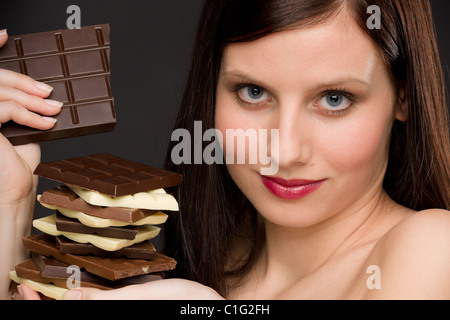 Cioccolato - Ritratto di donna sana gustare dolci su sfondo nero Foto Stock