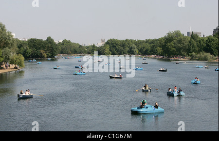 I membri del pubblico godetevi il bank holiday onda di calore da imbarcazioni a remi e utilizzando il pedalò su Hyde Park a serpentina del lago di Londra, Foto Stock