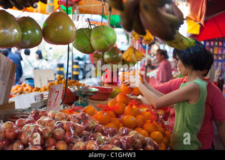 Donna shopping per la frutta a Bugis Street Market. Bugis, Singapore Foto Stock