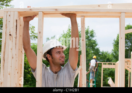 Carpenter il sollevamento di una scheda su framing Foto Stock