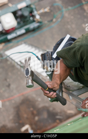 Falegname ispanica scaletta di arrampicata con martello e pistola a una casa in costruzione Foto Stock