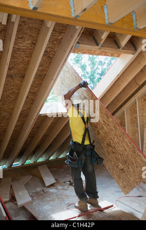 Carpenter il sollevamento di un pannello del tetto in corrispondenza di un sito in costruzione Foto Stock