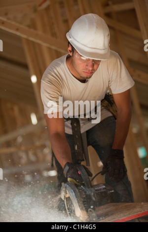 Carpenter utilizzando una sega circolare sul pannello del tetto di una casa in costruzione Foto Stock