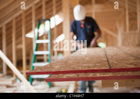 Carpenter utilizzando una sega circolare sul pannello di particelle in una casa in costruzione Foto Stock
