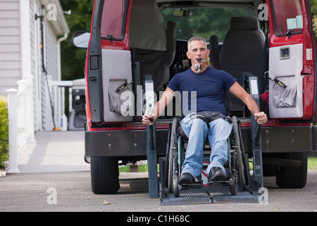 Uomo con lesioni al midollo spinale in una sedia a rotelle arrivare nel suo accessibile van Foto Stock