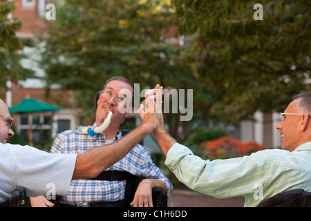 Tre uomini in carrozzina saluto ogni altro Foto Stock