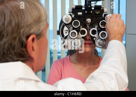 Oculista esaminando un occhi di donna con un phoropter Foto Stock