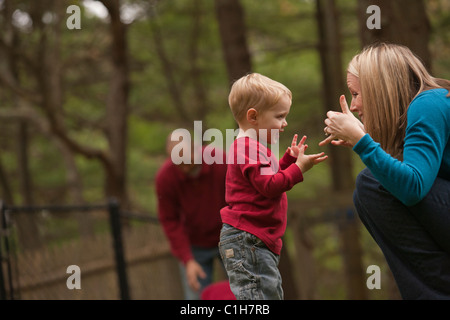 Donna firma la parola 'Play' in American Sign Language durante la comunicazione con il figlio in un parco Foto Stock