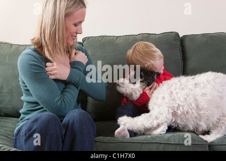 Donna firma la parola "abbraccio/amore' in American Sign Language con suo Figlio abbraccia un cane Foto Stock