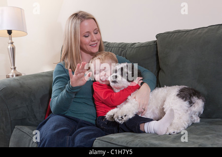 Donna firma la parola 'Cucciolo' in American Sign Language mentre suo figlio abbraccia un cane Foto Stock