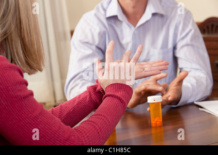 Donna firma la parola 'Sick' in American Sign Language durante la comunicazione con un uomo Foto Stock