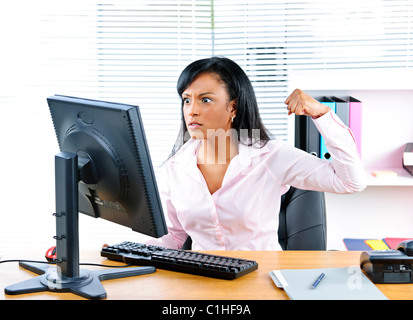 Arrabbiato giovane nero business donna punzonatura di computer in ufficio Foto Stock