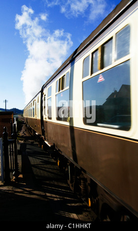 Treno di carrelli e attraversare il passaggio a livello Blu Stazione di ancoraggio verso Minehead, West Somerset, Inghilterra. Foto Stock