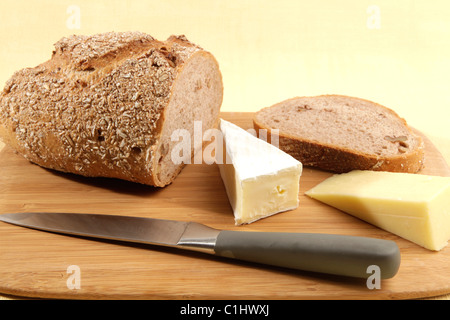Appena il granaio scolpito in legno di noce con pane e formaggio due cunei collocati su una tovaglia di colore giallo. Foto Stock