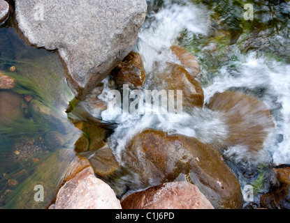 Guardando dritto verso il basso in corrispondenza di un piccolo ruscello che scorre su rocce colorate. Foto Stock