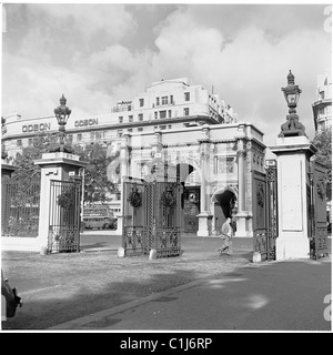 1950, l'uomo cammina oltre le porte all'estremità nord di Hyde Park, vicino al Marble Arch, il famoso monumento. Il cinema Odeon può essere visto sullo sfondo. Foto Stock