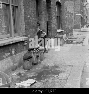 Anni '1950, un ragazzino con la madre all'ingresso di una casa a schiera vittoriana, affacciata sulla strada, a sud di Londra, in Inghilterra, nel Regno Unito. Foto Stock