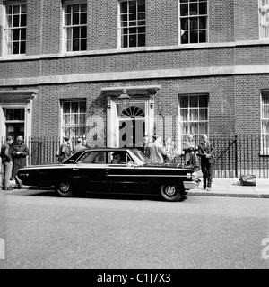 Londra,1960s, un conducente di una vettura americana attende come i giornalisti e i fotografi si raccolgono al di fuori n. 10 di Downing Street, la casa del Primo Ministro del Regno Unito. Foto Stock