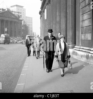 1950s, Città di Londra, impiegati che camminano vicino alla Banca d'Inghilterra, tra cui un gentiluomo in tuta e cravatta, un cappello da bowler e un ombrello. Foto Stock