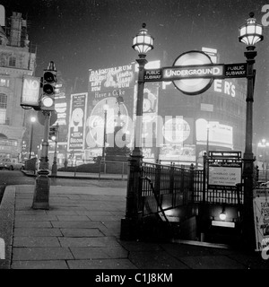 Anni '1950, storico, orario serale e cartelloni pubblicitari al neon al Piccadilly Circus, Londra, che illuminano il famoso punto di riferimento del West End. Foto Stock