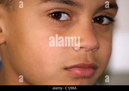 Il primo piano mostra un bel 7 anno vecchio bi-razziale ragazzo in faccia e grandi occhi marroni. Questa immagine è un estremo closeup e i lati Foto Stock