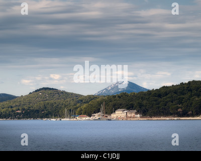 Costa adriatica con alcune vecchie case e con Osorscica hill in background, la cittadina di Mali Losinj, Croazia,l'Europa Foto Stock