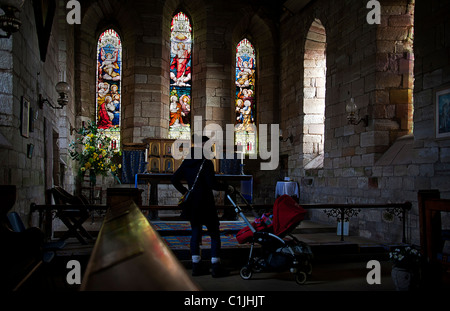 Giovane madre e bambino ammirando l'interno di St Marys la vergine. A Isola Santa di Lindisfarne. Northumberland.UK Foto Stock