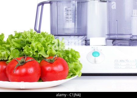 Pomodori con insalata verde e cucina processore sulla tavola bianco Foto Stock