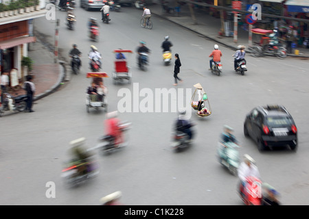 Un giogo solitario portante è circondato da ronzii moto su una strada trafficata in Hanoi, Vietnam. Foto Stock