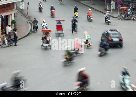 Un giogo solitario portante è circondato da ronzii moto su una strada trafficata in Hanoi, Vietnam. Foto Stock