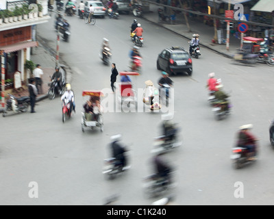Un giogo solitario portante è circondato da ronzii moto su una strada trafficata in Hanoi, Vietnam. Foto Stock