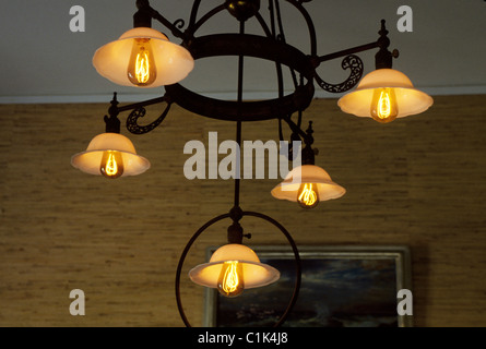 Inizio incandescente lampadine elettriche inventato da Thomas A. Edison sono illuminati in un vintage ferro battuto lampadario a Fort Myers, Florida, Stati Uniti d'America. Foto Stock