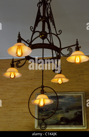 Inizio incandescente lampadine elettriche inventato da Thomas A. Edison sono illuminati in un vintage ferro battuto lampadario a Fort Myers, Florida, Stati Uniti d'America. Foto Stock