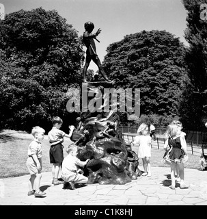 Anni '1950, estate e bambini piccoli che giocano alla statua di bronzo di Peter Pan a Kensington Gardens, Londra, un personaggio creato da J. M. Barrie. Foto Stock