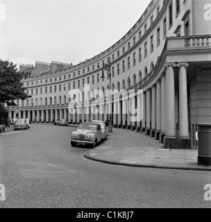 Anni '1950, auto storiche dell'epoca parcheggiate in una mezzaluna di grandi case Regency vicino a Regents Park, Londra, Inghilterra. Foto Stock