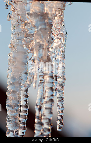 Ghiaccioli congelati hanging off grondaie su una casa suburbana Foto Stock