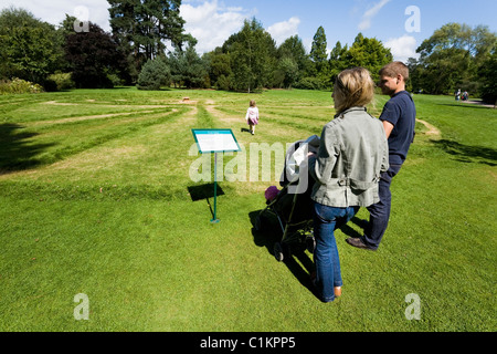 Famiglia donna / uomo / madre / padre e la PRAM / passeggino / sedia push camminare nel labirinto di erba. Wisley Gardens, Surrey. Regno Unito Foto Stock