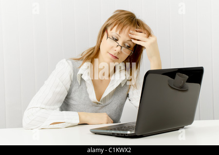 Stanco lavoratore in ufficio. Disheveled Ragazza con notebook Foto Stock