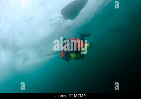 Scuba Diver in sidemount nuotare sotto il ghiaccio ice-immersioni nel lago Baikal, Siberia, Russia, isola di Olkhon. Foto Stock