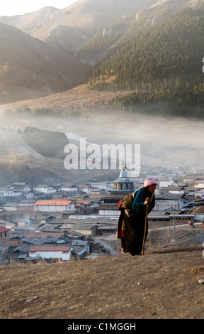 La mattina presto in Langmusi, Cina. Il Tibetano pellegrini a piedi su per la montagna su un locale Kora percorso intorno Langmusi. Foto Stock