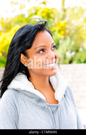 Felice giovane nero donna che guarda verso il lato esterno in autunno Foto Stock