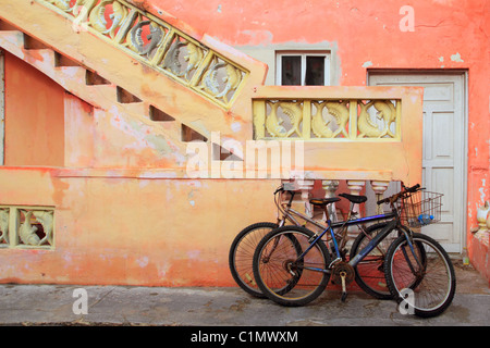 Biciclette su grunge tropicali dei Caraibi Orange facciata gialla Messico Foto Stock