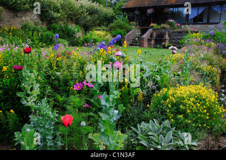 Un grazioso paese di lingua inglese Garden cottage con un sacco di fiori e un prato. Foto Stock