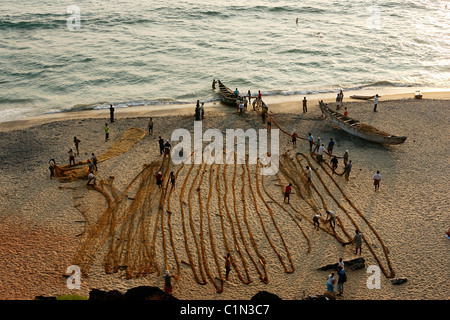 India Kerala, Varkala, pescatori tirare su reti dal mare al calar della sera Foto Stock